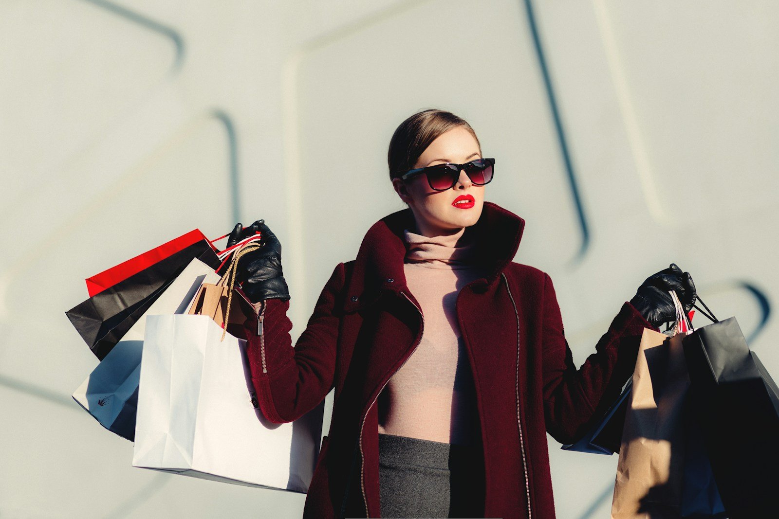 Woman in a burgundy coat carrying shopping bags